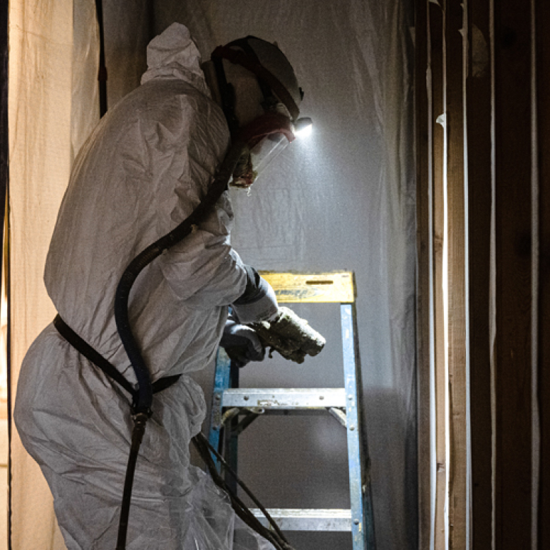 Foam insulation installation being carried out by a Farnum Insulation worker in a hazmat suit.